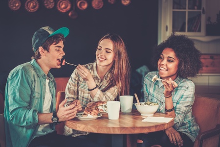 Cheerful multiracial friends eating in a cafeの写真素材