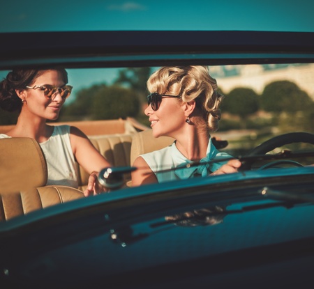 Two stylish ladies in a classic convertibleの写真素材
