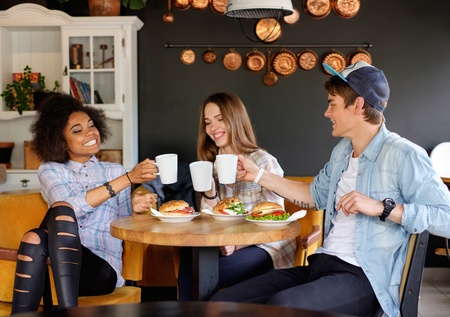 Cheerful multiracial friends eating in a cafeの写真素材