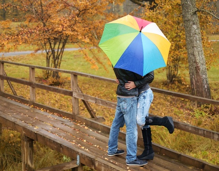 couple hiding under umbrella outdoors on beautiful rainy autumn dayの写真素材