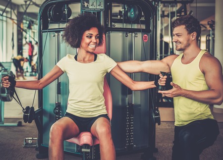 Trainer explaining how to use training machine in a gymの写真素材