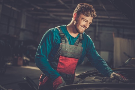 Mechanic checking under hood in a workshopの写真素材