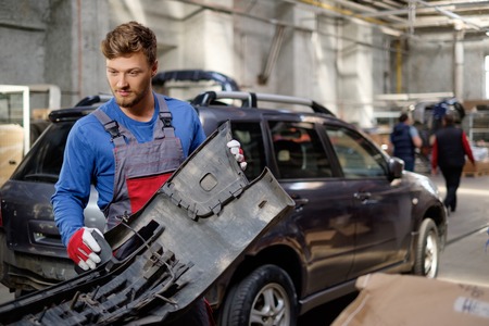 Mechanic with car bumper in a workshopの写真素材