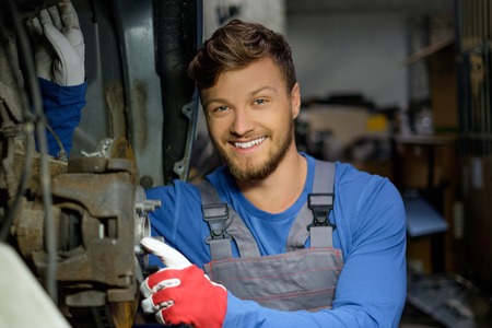Mechanic checking car brake system in a workshopの写真素材