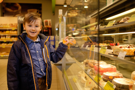 Little boy near display with cakes in a grocery storeの写真素材