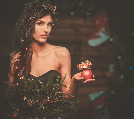 Woman in christmas tree dress in wooden interior holding christmas toyの写真素材