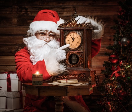 Santa Claus in wooden home interior showing time on a clockの写真素材