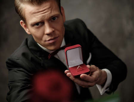 Man holding box with a proposal ring and red roseの写真素材