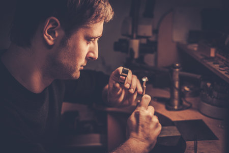 Jeweler looking at the ring through microscope in a workshop.の写真素材