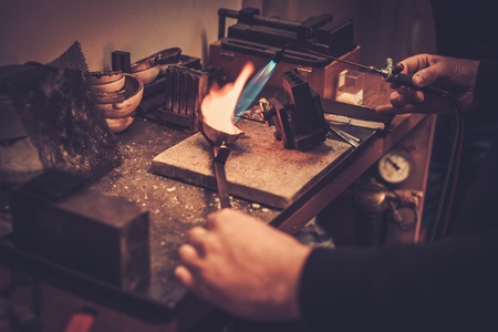 Goldsmith melting gold to liquid state in crucible with gasoline burner.の写真素材