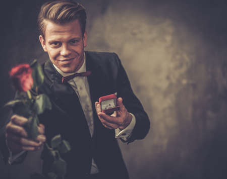 Man holding box with a proposal ring and red roseの写真素材