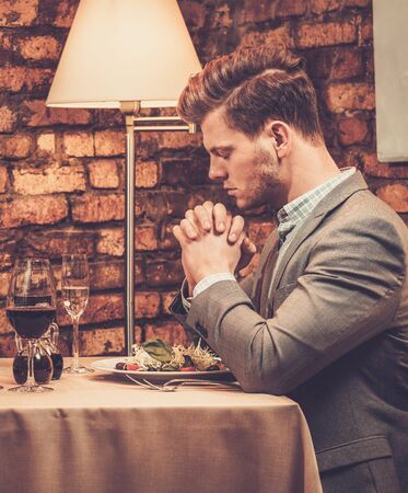 Stylish wealthy man pray before meal at restaurant.の写真素材