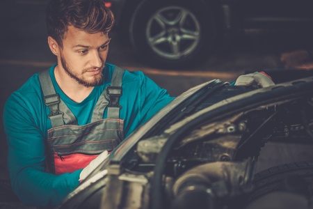 Mechanic with new car headlight in a workshopの写真素材
