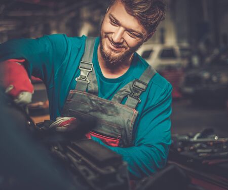 Mechanic checking under hood in a workshopの写真素材