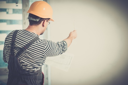 Foreman with construction plan in new building interior