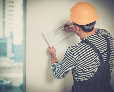 Foreman with construction plan in new building interior