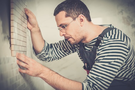 Builder applying tile on a wall