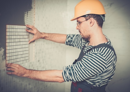 Builder applying tile on a wallの写真素材