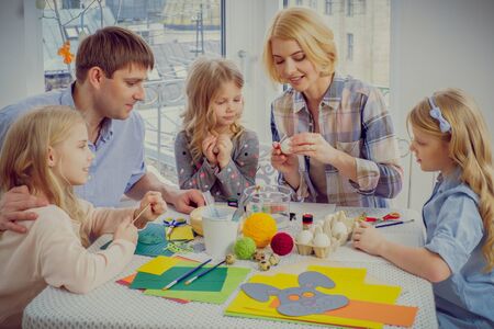 Cheerful family having fun painting and decorating easter eggs.の写真素材