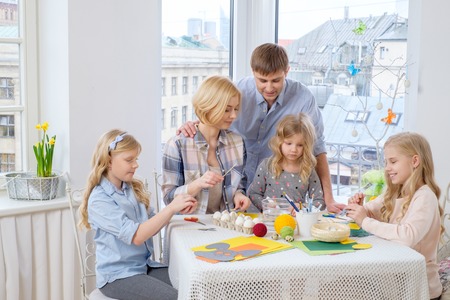 Cheerful family having fun painting and decorating easter eggs.