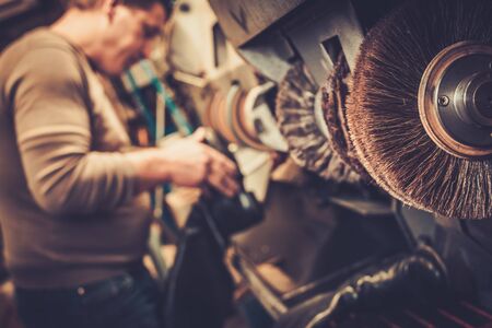 Shoemaker repairs shoes in the studio craft grinder machine.の写真素材