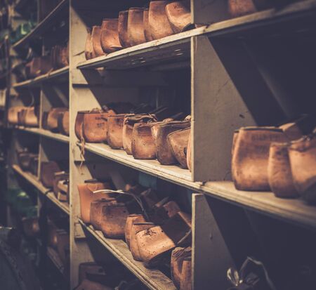 Various of vintage wooden shoe lasts in a row on the old shelves.の写真素材