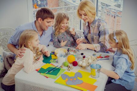 Cheerful family having fun painting and decorating easter eggs.