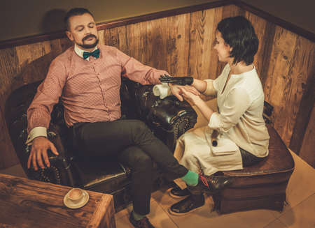 Confident old-fashioned man doing male manicure in a barber shop.