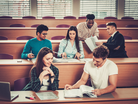 Multinational group of cheerful students taking an active part in a lesson while sitting in a lecture hall.の写真素材