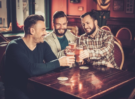 Cheerful old friends having fun and drinking draft beer in pub.の写真素材