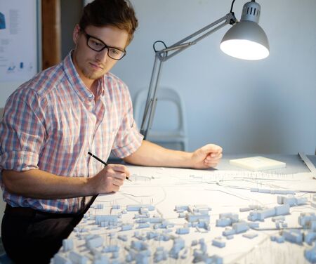 Young architect working on drawing table in architect studio.