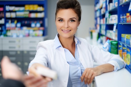 Beautiful smiling young woman pharmacist doing his work in pharmacy.の写真素材