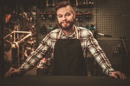Stylish bicycle mechanic standing in his workshop.の写真素材