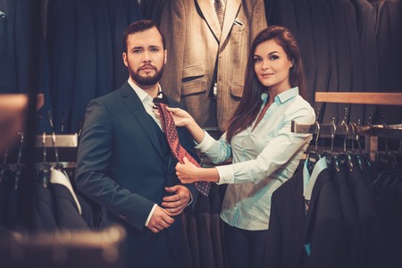 Confident handsome man with beard choosing a tie in a suit shop.の写真素材