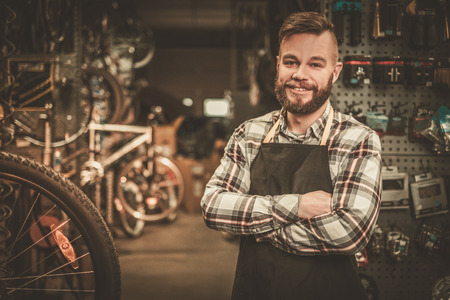 Stylish bicycle mechanic standing in his workshop.の写真素材