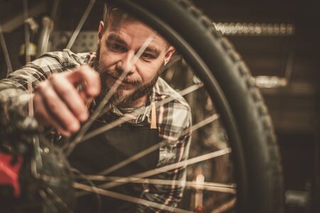Stylish bicycle mechanic doing his professional work in workshop.の写真素材