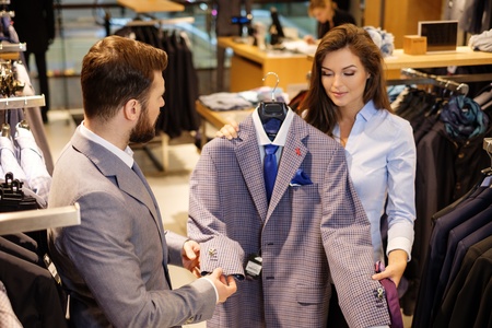 Confident handsome man with beard choosing a jacket in a suit shop.の写真素材