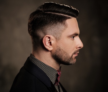 Well-groomed stylish young man with bow tie posing on dark background.の写真素材
