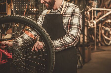 Stylish bicycle mechanic doing his professional work in workshop.の写真素材