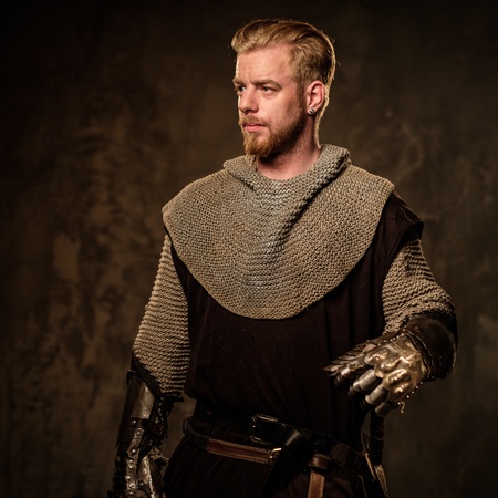 Young medieval knight posing on dark background.の写真素材