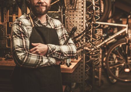 Stylish bicycle mechanic standing in his workshop.の写真素材