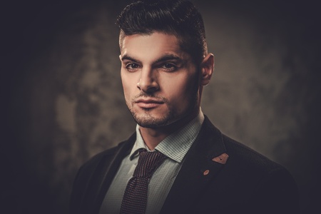 Serious well-dressed hispanic man posing on dark background.の写真素材