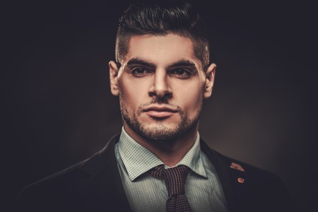 Serious well-dressed hispanic man posing on dark background.の写真素材