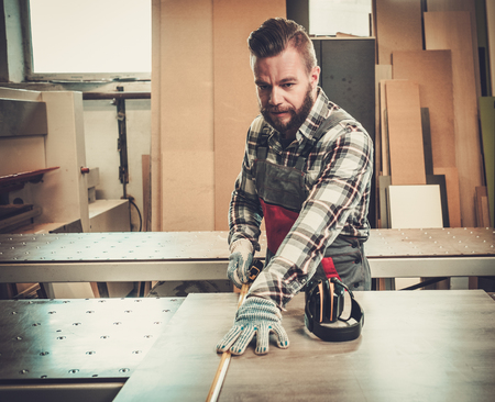 Carpenter works on wood plank in carpentry workshop.