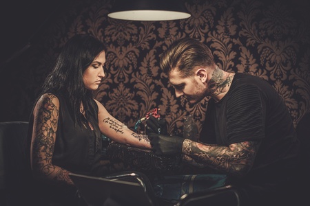 Professional tattoo artist makes a tattoo on a young girl's hand.の写真素材