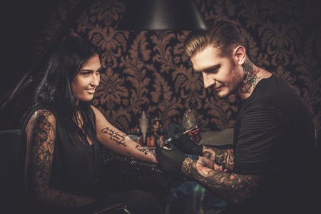 Professional tattoo artist makes a tattoo on a young girl's hand.の写真素材