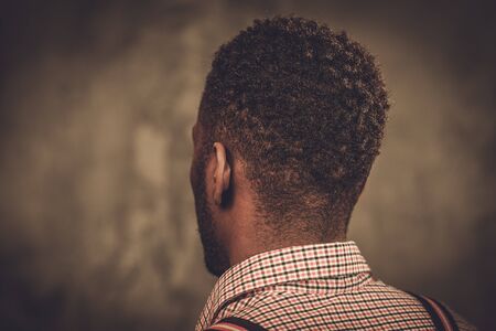 Stylish young black man with suspenders posing on dark background.の写真素材