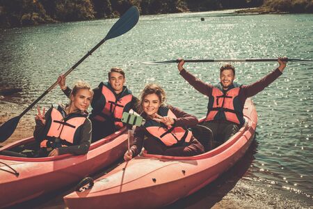 Cheerful friends taking selfie in kayaks on a beach.の写真素材