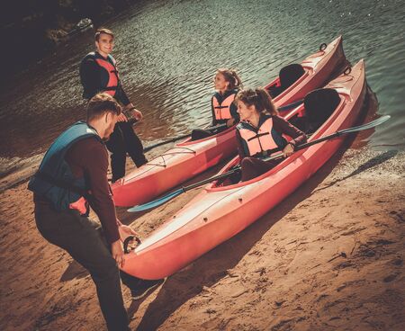 Cheerful friends having fun in kayaks on a beach.の写真素材