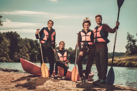 Cheerful friends having fun near kayaks on a beach.の写真素材